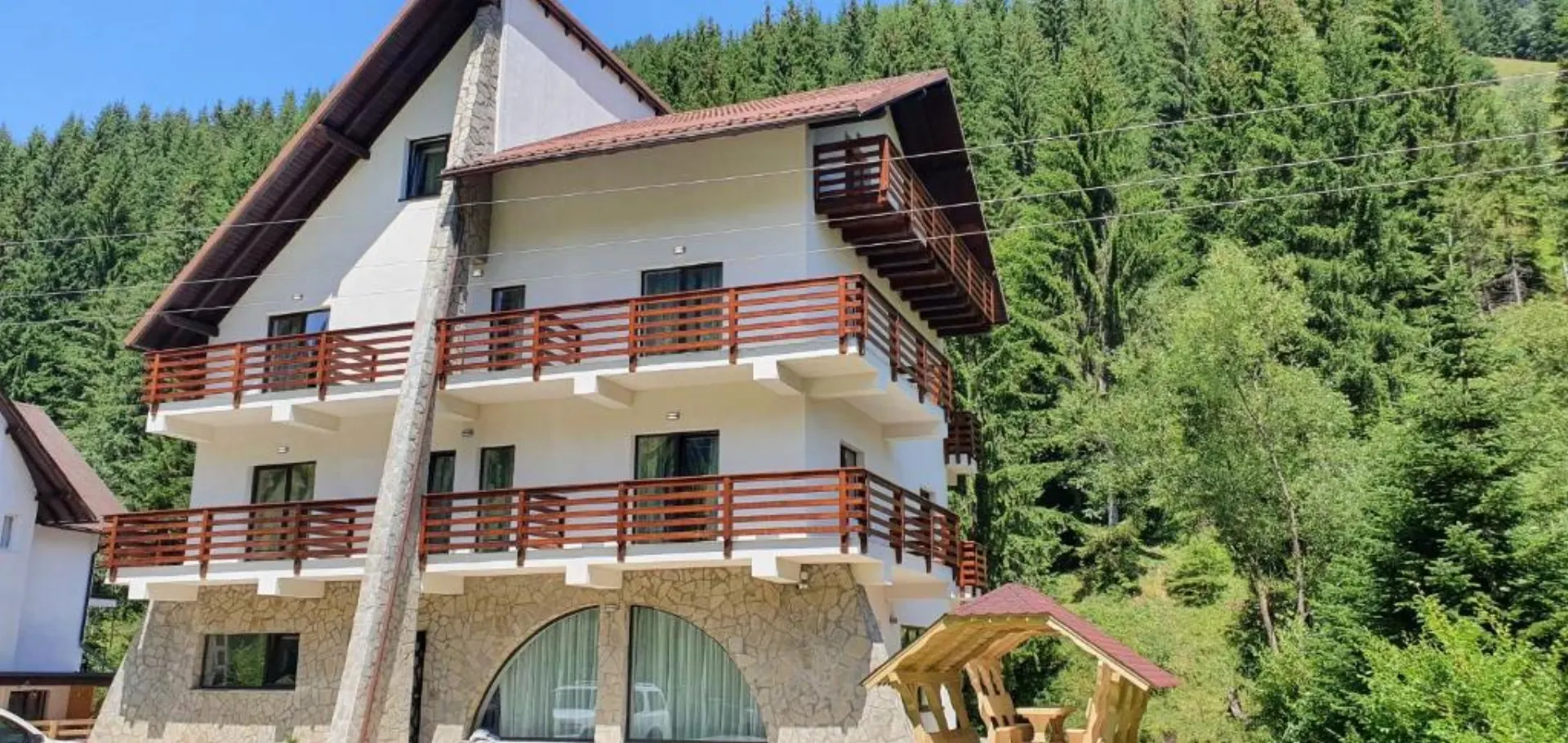 Fațada pensiunii Alegria — piatră, balcoane și pădure